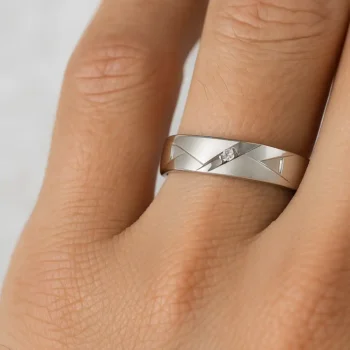 Elegant men's white gold diamond wedding ring with modern cut design shown on finger for scale