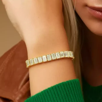 Elegant emerald cut diamond tennis bracelet in yellow gold showcased on woman’s wrist – lab-created diamond fine jewelry