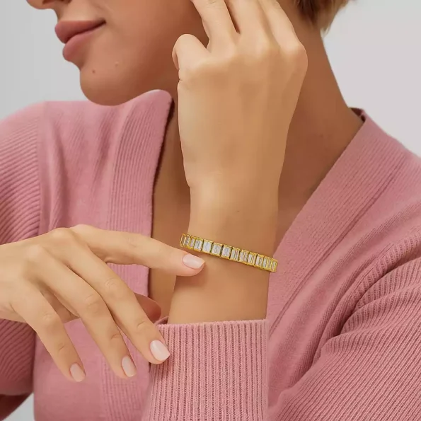Elegant emerald cut diamond tennis bracelet in yellow gold showcased on woman’s wrist – lab-created diamond fine jewelry