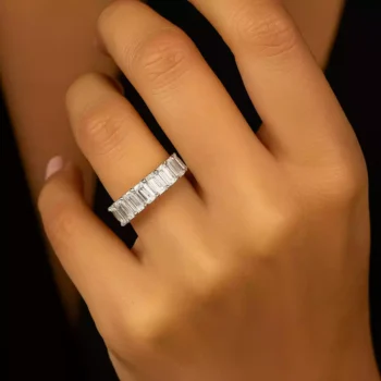 Emerald cut lab grown diamond eternity band ring on woman's hand in white gold setting