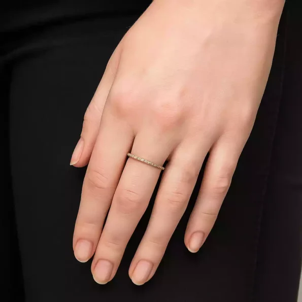 Delicate thin yellow gold diamond band worn on finger – minimalist engagement or stacking ring.