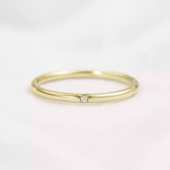 Matte finish yellow gold lab-grown diamond wedding band with flush pave setting on white fabric background