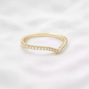 Yellow gold chevron diamond band ring with dainty pavé diamonds on soft white surface