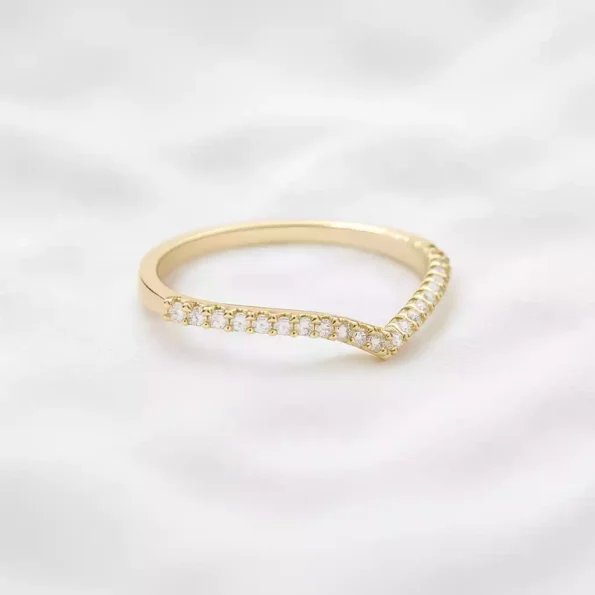 Yellow gold chevron diamond band ring with dainty pavé diamonds on soft white surface