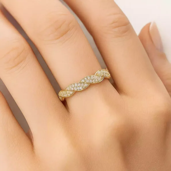 Yellow gold twisted diamond band ring worn on finger, elegant braided design with pave-set lab-grown diamonds