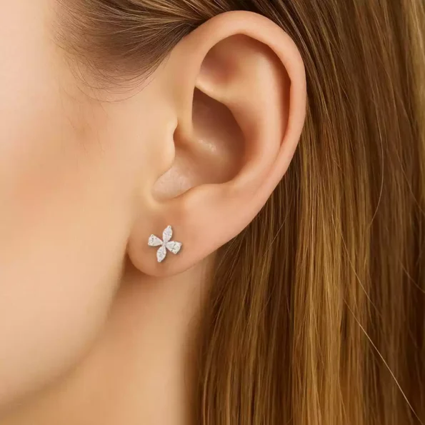 Floral diamond stud earrings worn on ear, showcasing petite flower petal design in white gold with sparkling marquise and pear diamonds