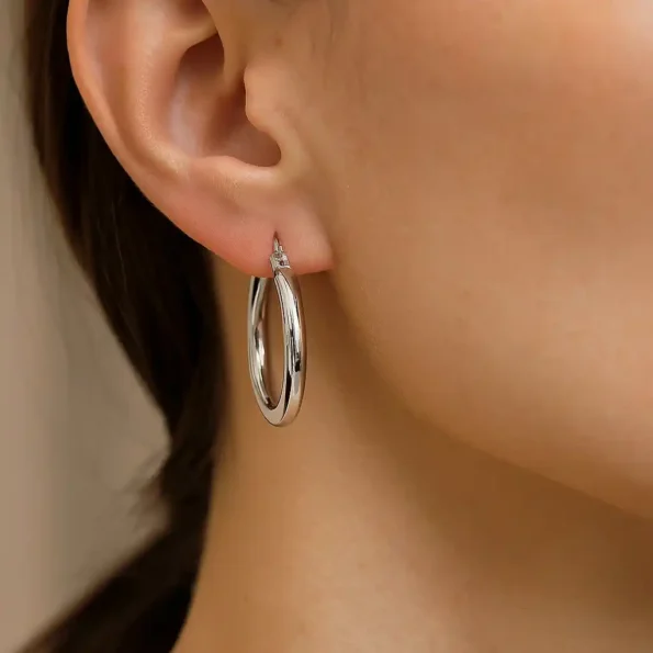 Woman wearing polished silver hoop earrings with a secure latch-back clasp