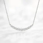 Front view of white gold journey-style necklace featuring graduated round lab-grown diamonds in a curved bar setting