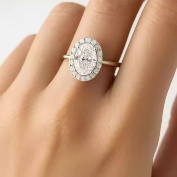 Oval diamond halo engagement ring worn on hand - lab diamond in 18K white gold setting