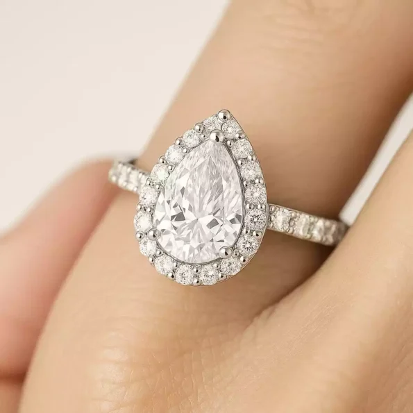 Pear shaped lab-created diamond halo engagement ring worn on hand – elegant look