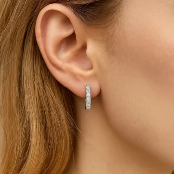 Minimalist pavé diamond huggie earrings in white gold shown on model's ear for scale and style