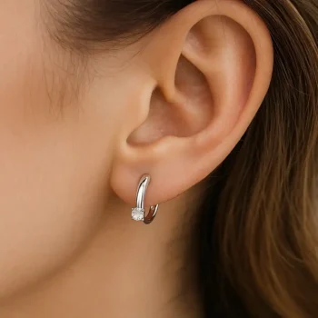 Round solitaire diamond hoop earring in white gold worn on female ear for scale and fit