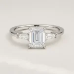 Front view of three-stone emerald cut lab-grown diamond engagement ring in white gold with tapered baguette side stones