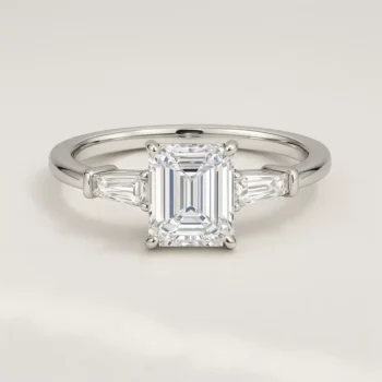 Front view of three-stone emerald cut lab-grown diamond engagement ring in white gold with tapered baguette side stones