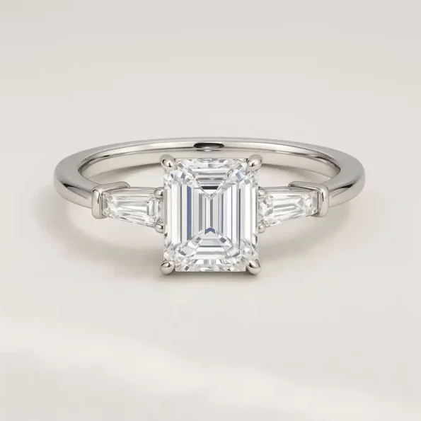 Front view of three-stone emerald cut lab-grown diamond engagement ring in white gold with tapered baguette side stones