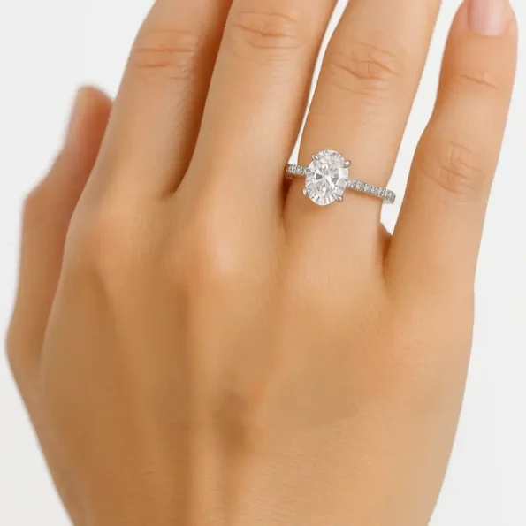 Elegant oval cut lab diamond ring with pavé band in white gold worn on woman's hand